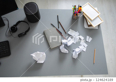 Messy home office desk with scattered paper and supplies. Creative block, frustration and domestic disorder in a modern living space. 124624189