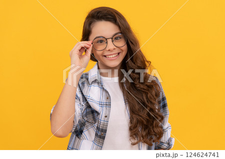cheerful teen girl in checkered shirt and glasses on yellow background 124624741