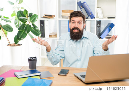 Perplexed guy making helpless gesture working at office desk, perplexity 124625033