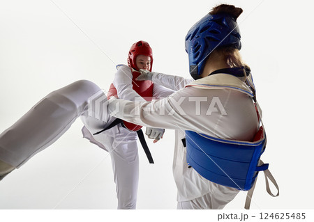 Female taekwondo athlete in red gear getting hit with precision punch by blue opponent in heated duel. Female taekwondo athlete in red gear getting hit with precision punch by blue opponent in heated duel. 124625485