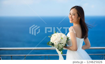 幸せそうな笑顔の白いウエディングドレスを着てブーケを持った女性と青い海。 幸せそうな笑顔の白いウエディングドレスを着てブーケを持った女性と青い海。 124625826