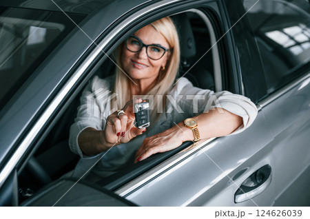 Looking through the opened window. Woman in white formal clothes is in the car dealership Looking through the opened window. Woman in white formal clothes is in the car dealership 124626039