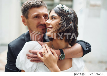Embracing each other. Beautiful bride with his fiance is celebrating wedding outdoors 124626200