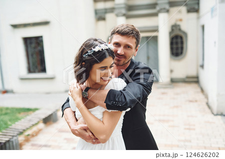 Embracing each other. Beautiful bride with his fiance is celebrating wedding outdoors 124626202