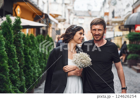 Walking by a street. Beautiful bride with his fiance is celebrating wedding outdoors Walking by a street. Beautiful bride with his fiance is celebrating wedding outdoors 124626254