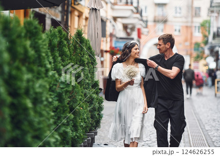 On the street with green plants on the left side. Beautiful bride with his fiance is celebrating wedding outdoors 124626255