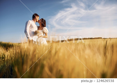 Embracing each other. Couple just married. Together on the majestic agricultural field at sunny day Embracing each other. Couple just married. Together on the majestic agricultural field at sunny day 124626538
