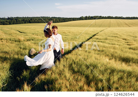 In dress and formal clothes. Couple just married. Together on the majestic agricultural field at sunny day 124626544