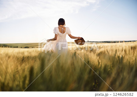 Enjoying the nature. Beautiful young bride in white dress is on the agricultural field at sunny day 124626582