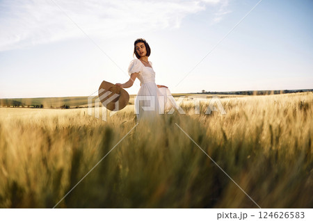 Enjoying the nature. Beautiful young bride in white dress is on the agricultural field at sunny day Enjoying the nature. Beautiful young bride in white dress is on the agricultural field at sunny day 124626583