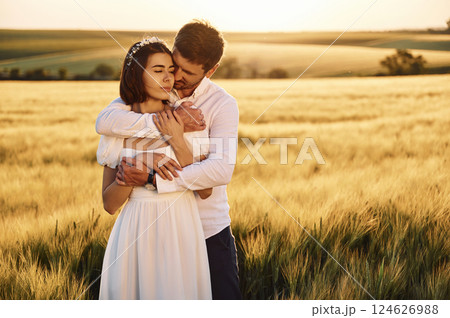 Front view. Embracing each other. Couple just married. Together on the majestic agricultural field at sunny day 124626988