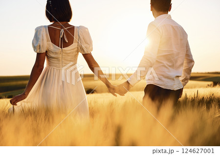 Rear view. Couple just married. Together on the majestic agricultural field at sunny day Rear view. Couple just married. Together on the majestic agricultural field at sunny day 124627001