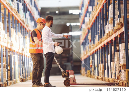Standing and working together. Two men in storage is in the warehouse Standing and working together. Two men in storage is in the warehouse 124627150