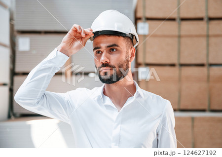 In white hard hat. Storage worker is in the warehouse with bunch of products In white hard hat. Storage worker is in the warehouse with bunch of products 124627192