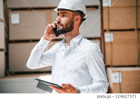 Having conversation by phone. Storage worker is in the warehouse with bunch of products 124627371