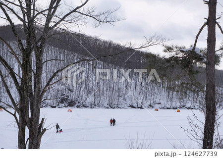 厳寒のさなか岩洞湖に厚い氷が張ったのでワカサギ釣りをする人と氷上のテント 厳寒のさなか岩洞湖に厚い氷が張ったのでワカサギ釣りをする人と氷上のテント 124627739