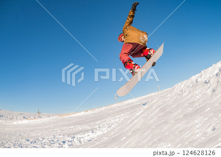 Snowboarder jumping against blue sky Snowboarder jumping against blue sky 124628126