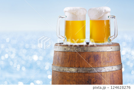 mugs of beer on wooden barrel over sea background mugs of beer on wooden barrel over sea background 124628276