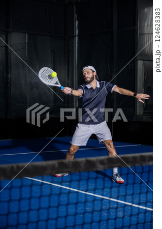 Padel player hitting ball with a racket 124628383