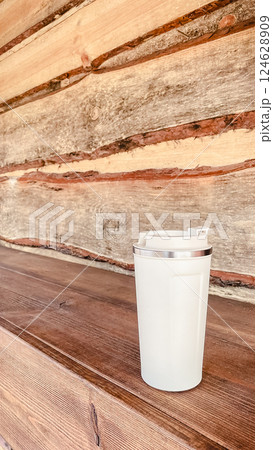 beige thermos mug in hand during walk in park 124628909