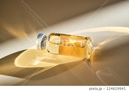 Injection vial with medicinal product in sunlight on beige background. 124629941