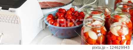 Canning ripe tomatoes and fresh tomato juice, preserving their natural taste for the winter months in airtight jars, kitchen table with prepared jars of tomatoes 124629943