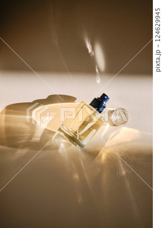 Perfume on a beige background in the rays of bright sun with beautiful highlights. 124629945