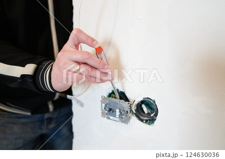 Electrician's hands check the current in the outlet using an indicator screwdriver. Replacing the electrical outlet. High quality photo Electrician's hands check the current in the outlet using an indicator screwdriver. Replacing the electrical outlet. High quality photo 124630036