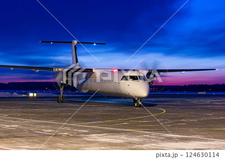 White passenger turboprop airliner taxiing through an airport at dawn 124630114
