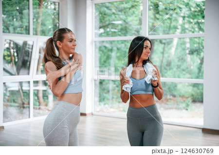 Two women in sportive clothes standing in the gym together Two women in sportive clothes standing in the gym together 124630769