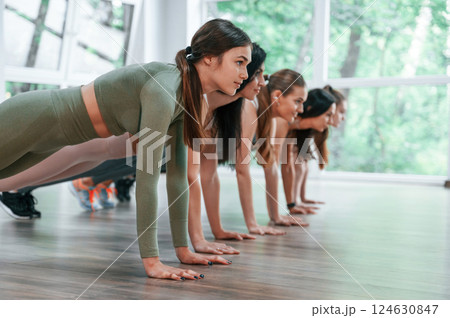 Doing plank. Group of women practicing fitness in the gym 124630847