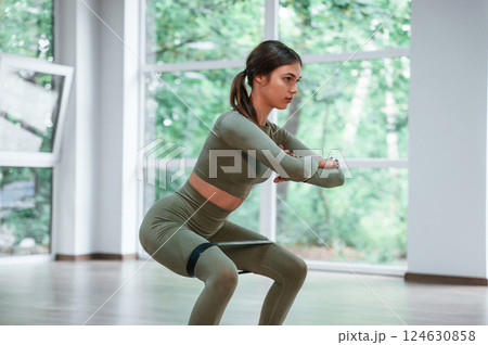 Doing squats. Woman in sportive clothes is having fitness day in the gym Doing squats. Woman in sportive clothes is having fitness day in the gym 124630858