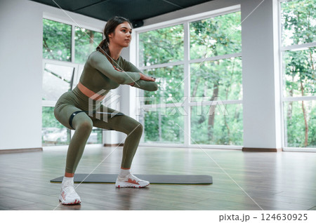 Doing squats. Woman in sportive clothes is having fitness day in the gym Doing squats. Woman in sportive clothes is having fitness day in the gym 124630925