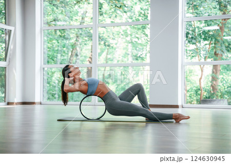 Circle for the spine. Woman in sportive clothes is having fitness day in the gym Circle for the spine. Woman in sportive clothes is having fitness day in the gym 124630945