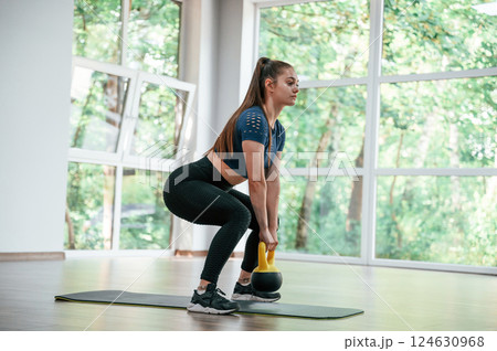 Holding weight for lifting. Woman in sportive clothes is having fitness day in the gym 124630968