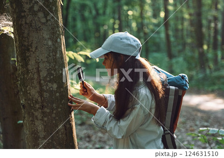 With magnifying glass. Girl is in the forest at summer day time discovering new places 124631510