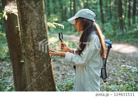 With magnifying glass. Girl is in the forest at summer day time discovering new places 124631511