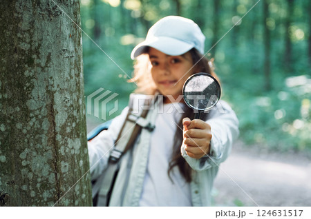 Using magnifying glass. Girl is in the forest at summer day time discovering new places 124631517