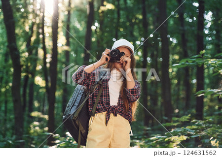 Young photographer with camera. Girl is in the forest at summer day time discovering new places Young photographer with camera. Girl is in the forest at summer day time discovering new places 124631562