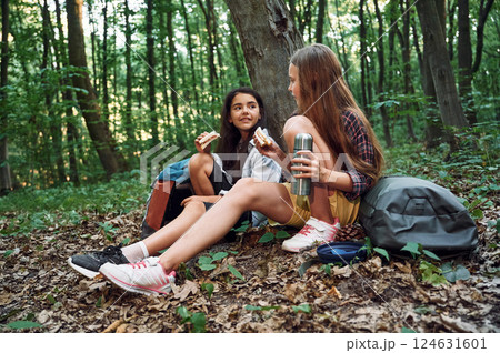 Sitting and eating. Two girls is in the forest having a leisure activity, discovering new places Sitting and eating. Two girls is in the forest having a leisure activity, discovering new places 124631601
