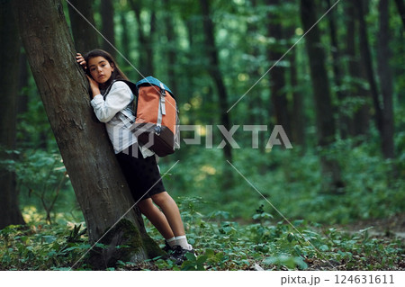 Leaning on the tree. Girl is in the forest at summer day time discovering new places 124631611