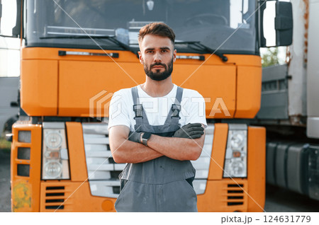 Standing and posing for the camera. Man in unifrom doing service for big truck vehicle Standing and posing for the camera. Man in unifrom doing service for big truck vehicle 124631779