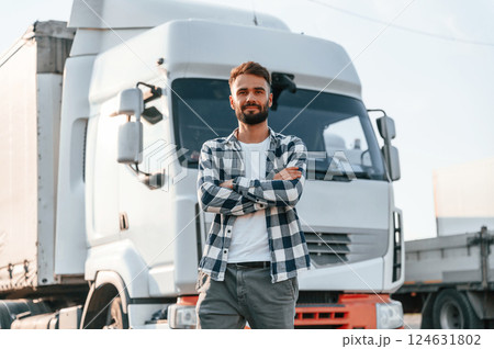 With arms crossed. Young truck driver is with his vehicle at daytime 124631802