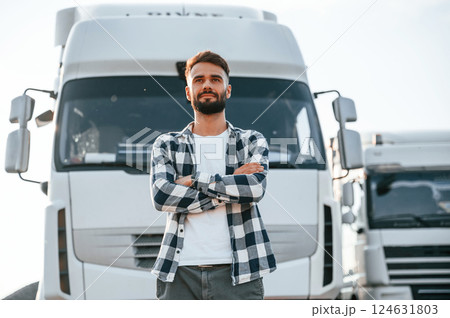 With arms crossed. Young truck driver is with his vehicle at daytime 124631803