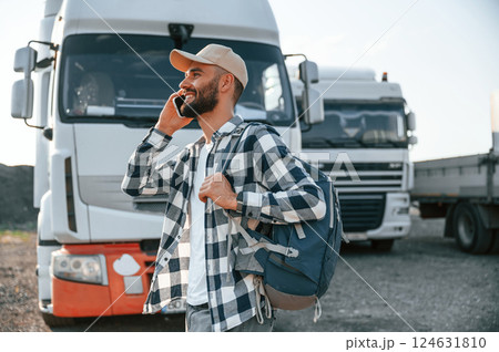 Standing outdoors. Young truck driver is with his vehicle at daytime 124631810