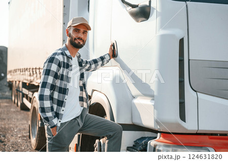 Standing by the door. Young truck driver is with his vehicle at daytime Standing by the door. Young truck driver is with his vehicle at daytime 124631820