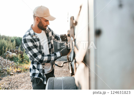 Checking the ropes. Young truck driver is with his vehicle at daytime 124631823