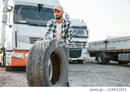With broken tire. Young truck driver is with his vehicle at daytime With broken tire. Young truck driver is with his vehicle at daytime 124631841
