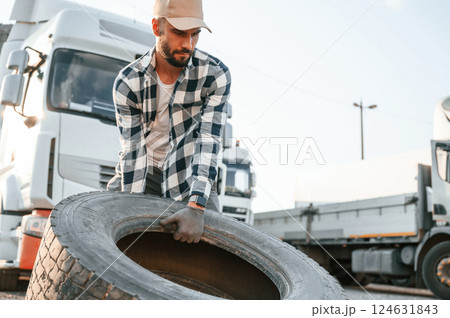 With broken tire. Young truck driver is with his vehicle at daytime With broken tire. Young truck driver is with his vehicle at daytime 124631843