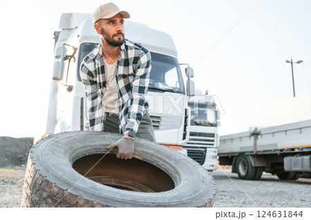 With broken tire. Young truck driver is with his vehicle at daytime With broken tire. Young truck driver is with his vehicle at daytime 124631844